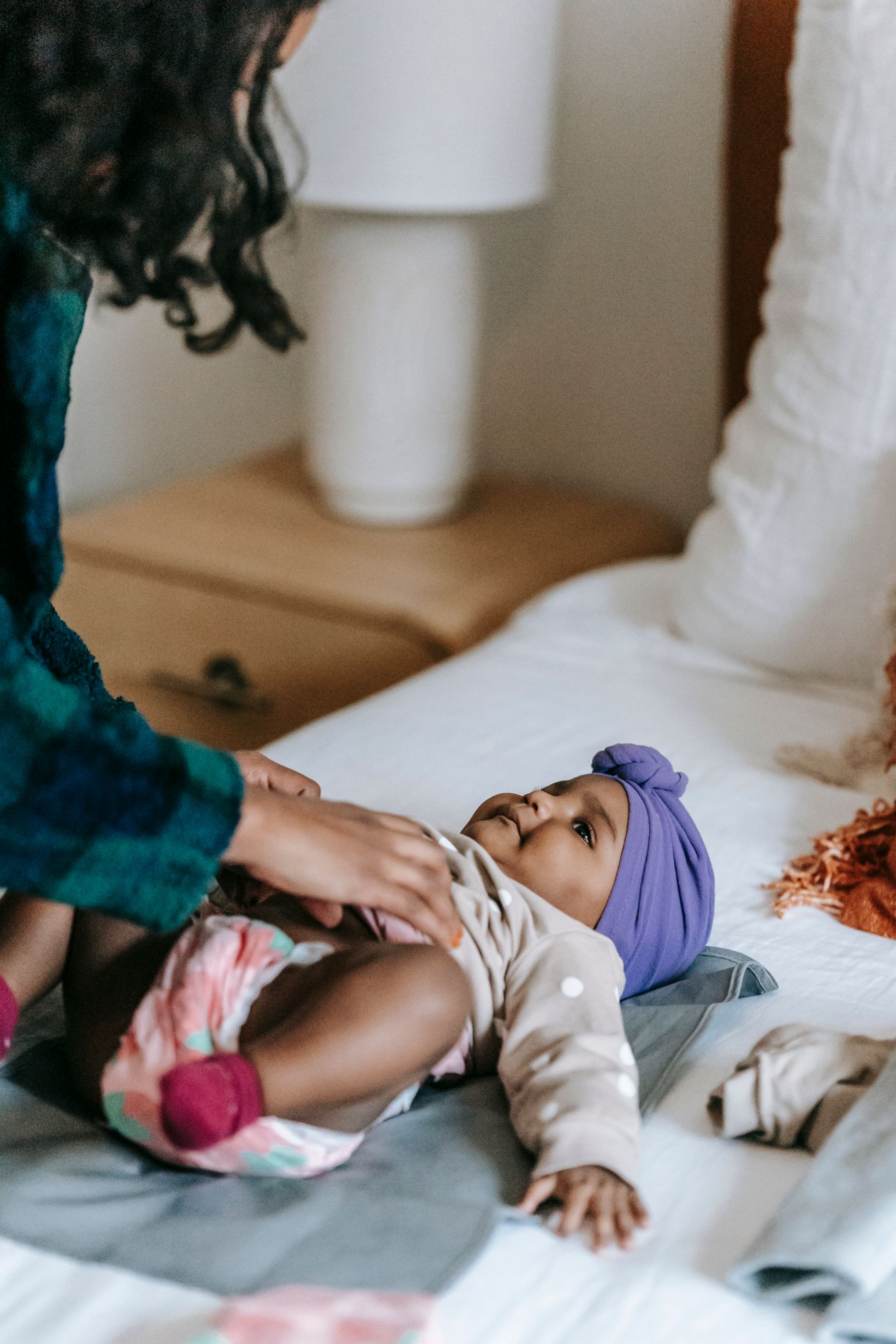 A mother dressing her awake baby on a changing mat